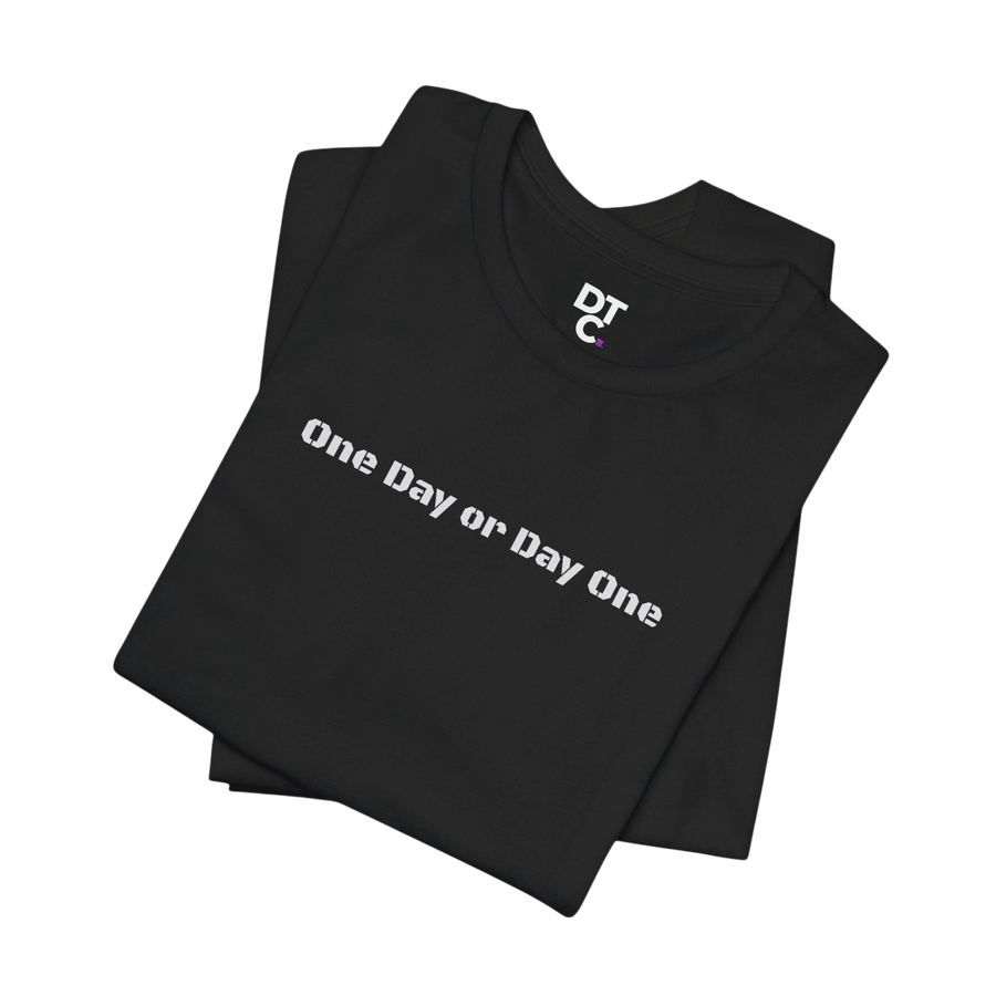 DailyThreadCo. black 100% cotton crew neck t-shirt with white "One Day or Day One" graphic text on front.