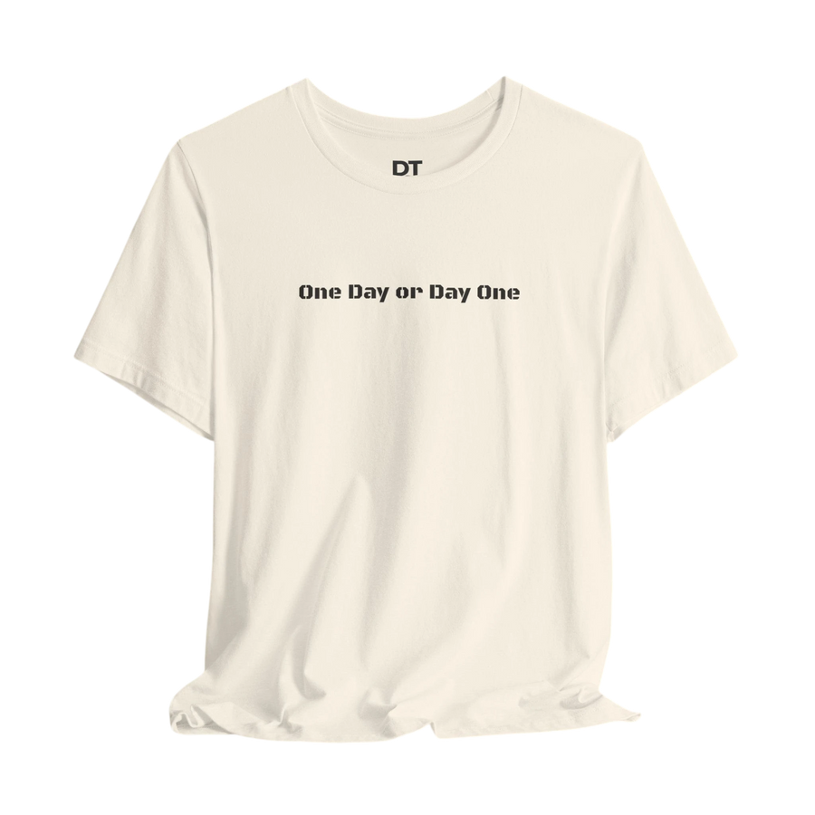DailyThreadCo. cream 100% cotton crew neck t-shirt with black text 'One Day or Day One' and 'DT' logo on the chest.