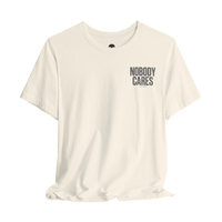 DailyThreadCo. cream cotton graphic tee with Nobody Cares text on the chest, featuring a crew neck and retail fit.
