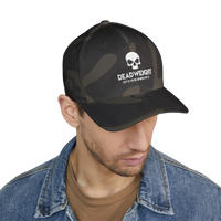 DailyThreadCo. camo Flexfit cap with distressed skull embroidery and Deadweight text on a man in a denim jacket.