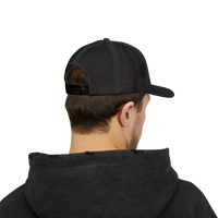 DailyThreadCo. black trucker cap with mesh back and adjustable snapback worn by a man in a black hoodie
