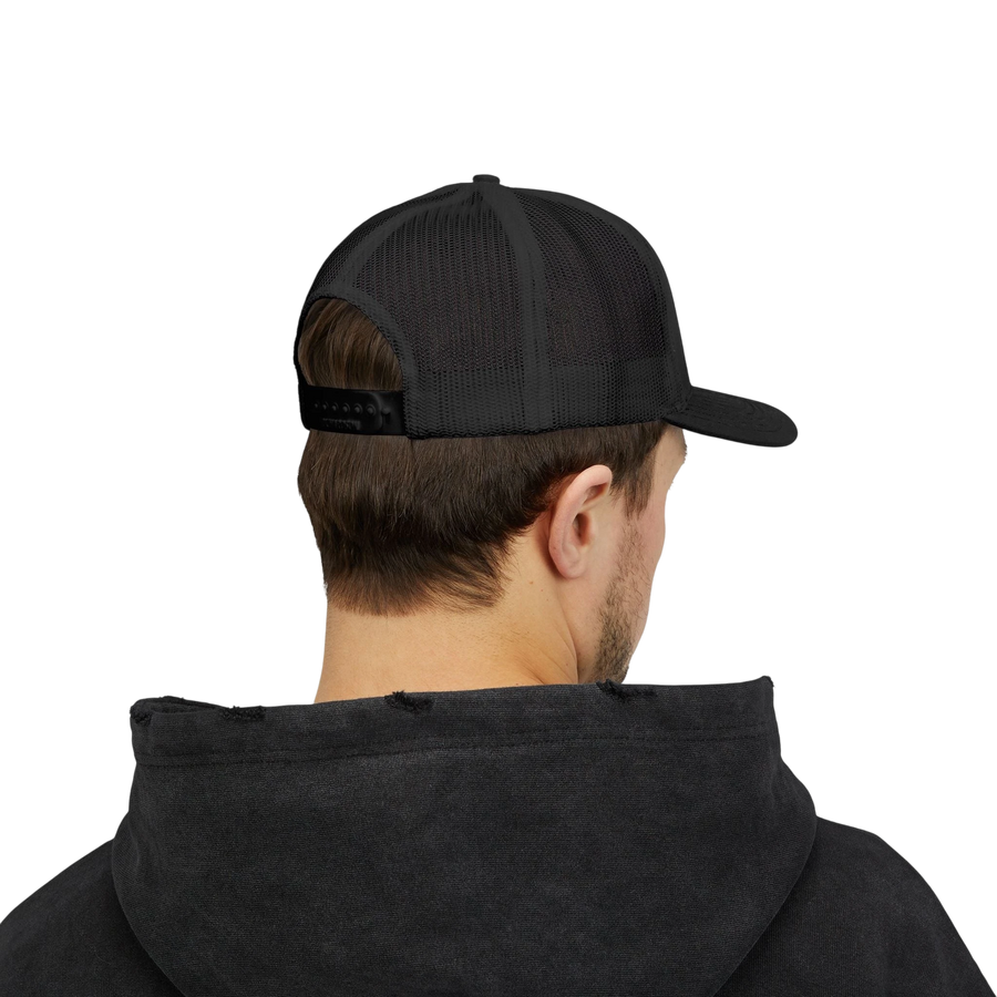 DailyThreadCo. black trucker cap with mesh back and adjustable snapback worn by a man in a black hoodie