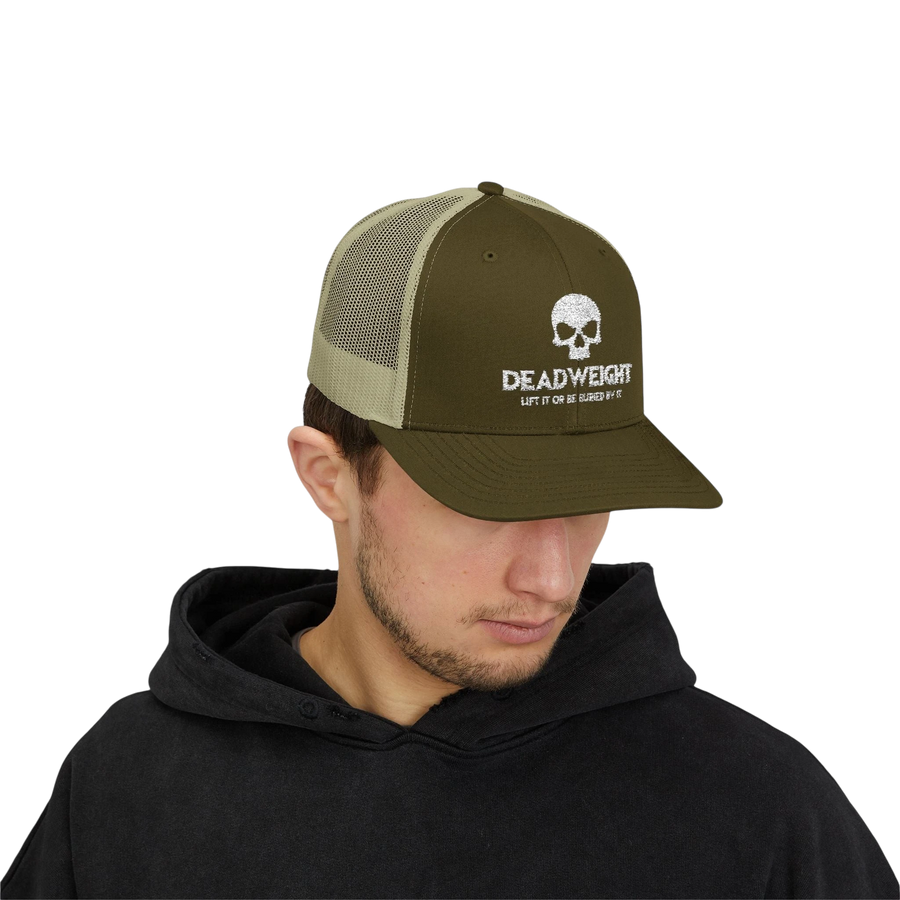 DailyThreadCo. olive green and tan trucker cap with white skull Deadweight logo worn by a man in a black hoodie.