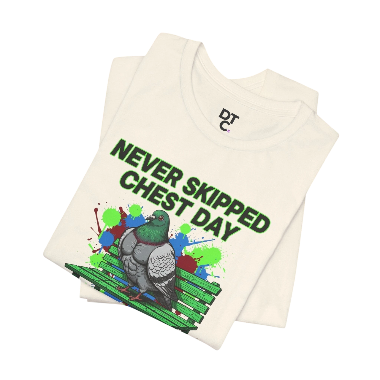 DailyThreadCo. cream cotton t-shirt with a graphic of a muscular pigeon on a green bench, surrounded by colorful paint splatters and the text "NEVER SKIPPED CHEST DAY."