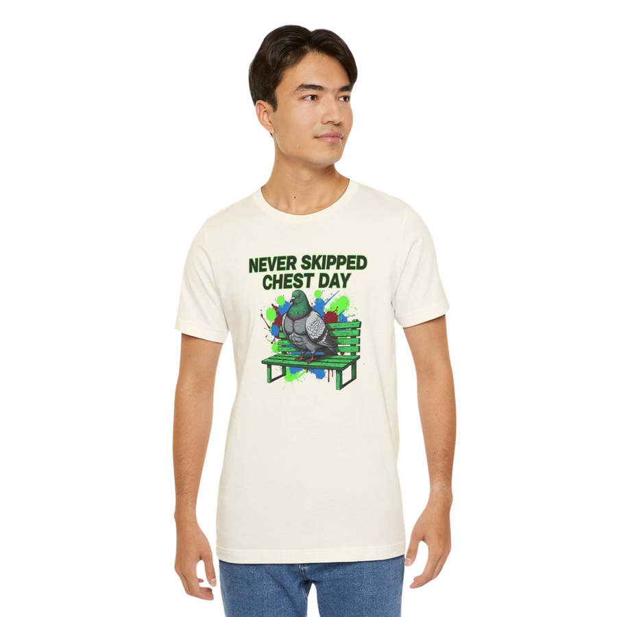 DailyThreadCo. cream cotton t-shirt with a graphic print of a muscular pigeon sitting on a green park bench. Text reads "NEVER SKIPPED CHEST DAY".