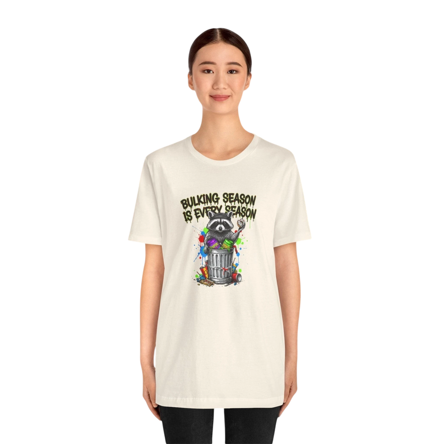 DailyThreadCo. cream 100% cotton t-shirt with a graphic of a raccoon in a trash can, text reads "BULKING SEASON IS EVERY SEASON".