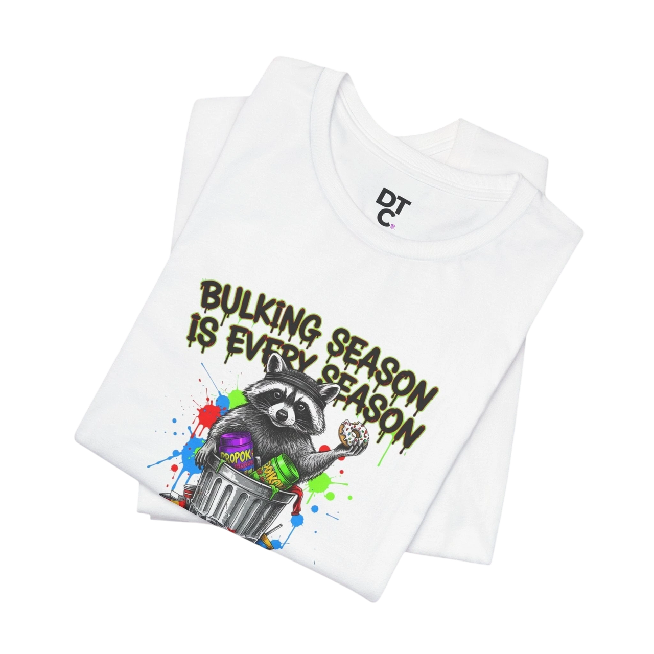 DailyThreadCo. white 100% cotton t-shirt with a funny graphic of a raccoon in a trash can holding a donut and the text "BULKING SEASON IS EVERY SEASON".