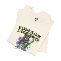 DailyThreadCo. cream 100% cotton t-shirt with a graphic of a raccoon in a trash can holding a donut, with the text 
