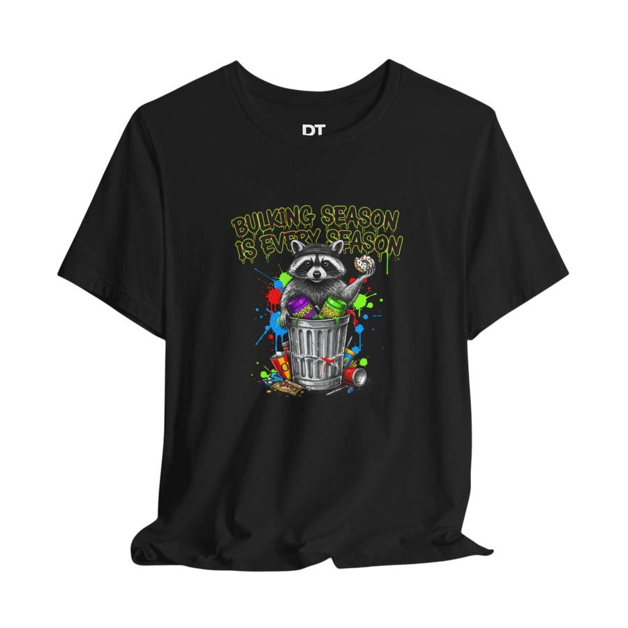 DailyThreadCo. black 100% cotton t-shirt with a funny graphic of a raccoon in a trash can, holding a donut, with colorful paint splatters and the text "BULKING SEASON IS EVERY SEASON".