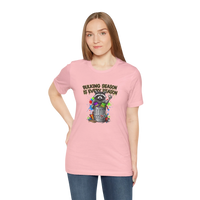 DailyThreadCo. pink 100% cotton t-shirt with a graphic of a raccoon in a trash can, surrounded by paint splatters and the text 