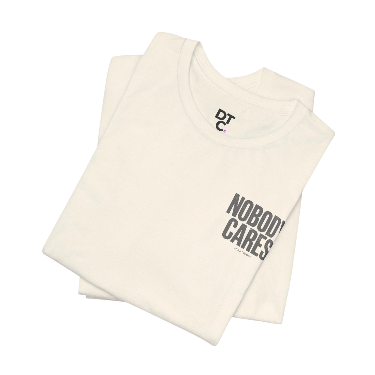 DailyThreadCo. cream 100% cotton graphic tee with "NOBODY CARES" text art on front and DTC logo on neck.