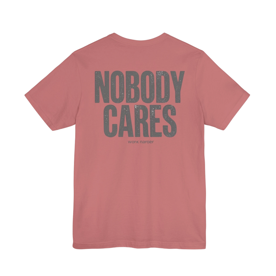 DailyThreadCo. Dusty rose 100% cotton t-shirt with distressed grey "NOBODY CARES" graphic and "work harder" text.
