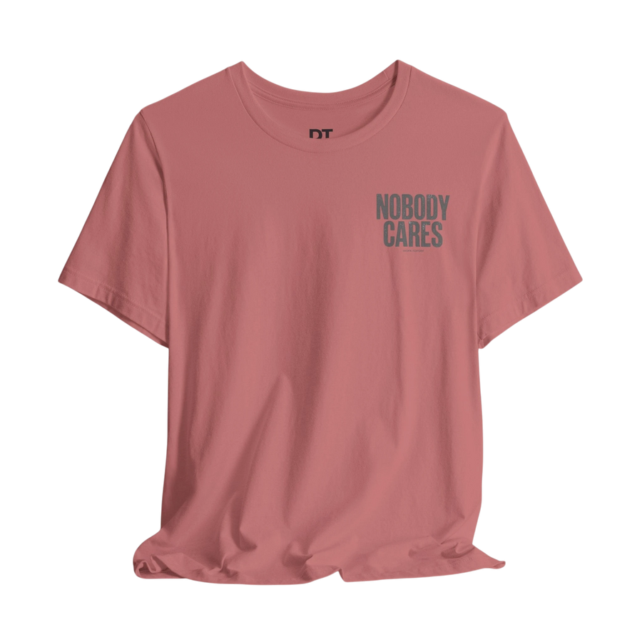 DailyThreadCo. dusty rose 100% cotton graphic tee with "Nobody Cares" text on the chest.