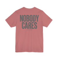 DailyThreadCo. dusty rose graphic t-shirt with Nobody Cares text in grey on the back, made from soft cotton.