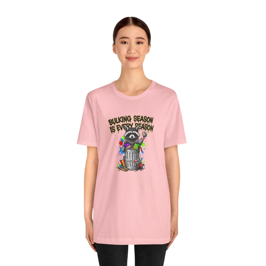 DailyThreadCo. pink cotton t-shirt with a graphic of a raccoon in a trash can with the text "BULKING SEASON IS EVERY SEASON".