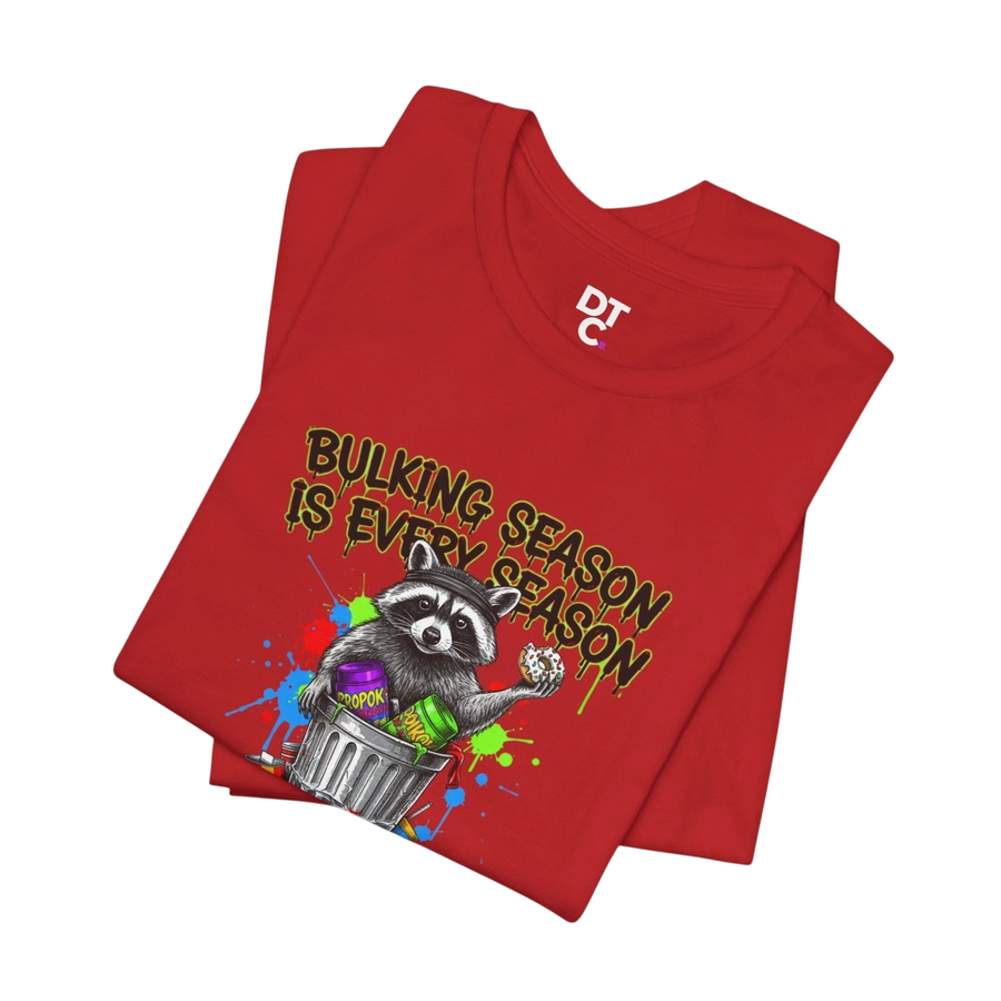 DailyThreadCo red 100% cotton t-shirt with a funny graphic of a raccoon in a trash can with the text "BULKING SEASON IS EVERY SEASON".