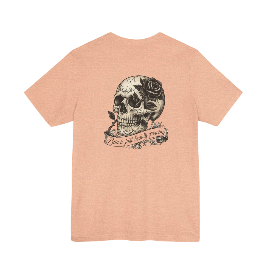 DailyThreadCo. peach cotton tee with hand-drawn skull and rose graphic on back. Text reads "Pain is just beauty growing".
