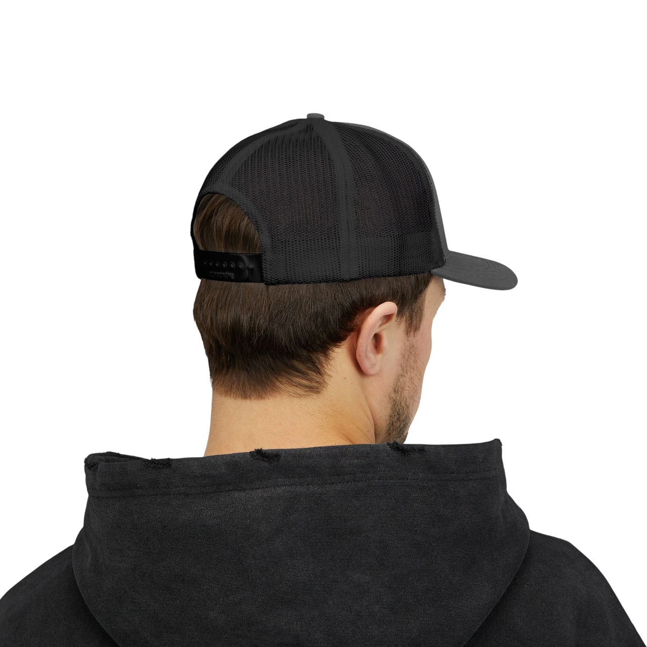 DailyThreadCo. black trucker cap with mesh back and adjustable snap closure worn by a man in a dark hoodie.