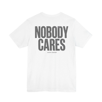DailyThreadCo. white cotton graphic t-shirt featuring Nobody Cares text on the back in a distressed grey font.